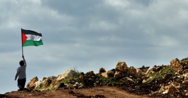 A boy holds a Palestinian flag during a march against the construction of a section of Israel's separation barrier in the outskirts of the village of Iskaka, near the Jewish West Bank settlement of Ariel, Palestine, Jan. 25, 2005. (AP File Photo)