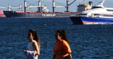 Two women pass on the river bank as the Türkiye-flagged TQ Samsunhe, the last grain ship that left a Ukrainian port since Russia exited the grain corridor agreement one day earlier, is seen in the Marmara Sea, in Istanbul, Türkiye, July 18, 2023. (EPA Photo)
