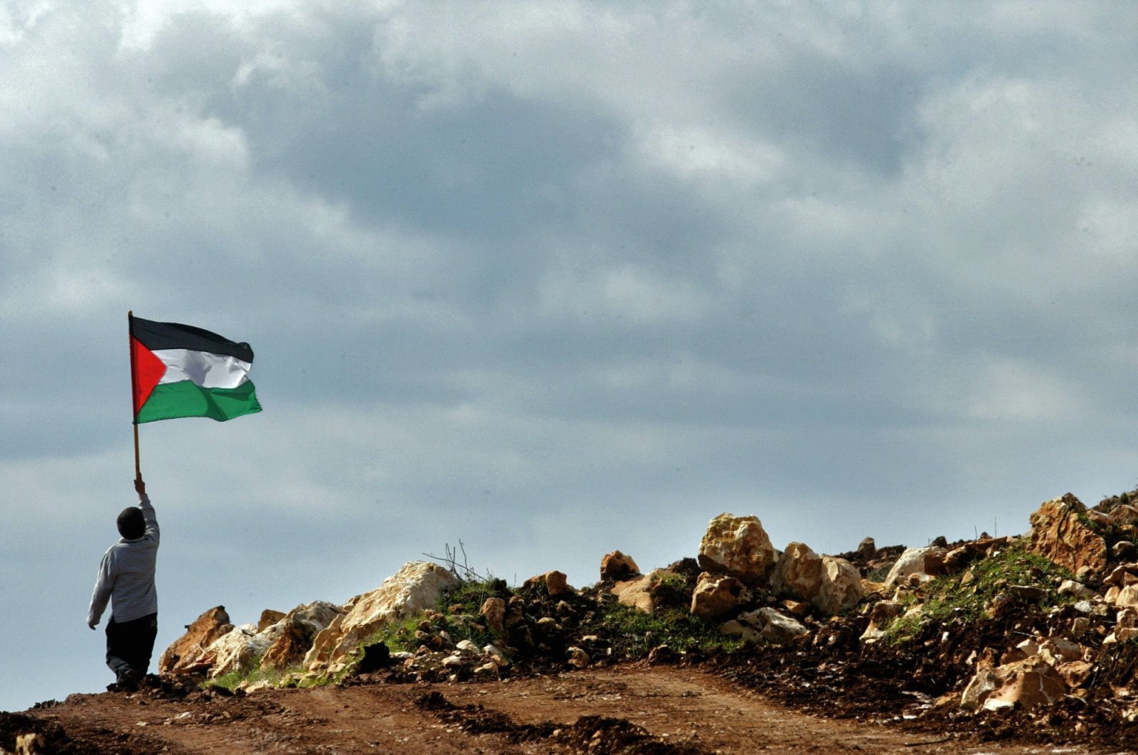 A boy holds a Palestinian flag during a march against the construction of a section of Israel&#039;s separation barrier in the outskirts of the village of Iskaka, near the Jewish West Bank settlement of Ariel, Palestine, Jan. 25, 2005. (AP File Photo)