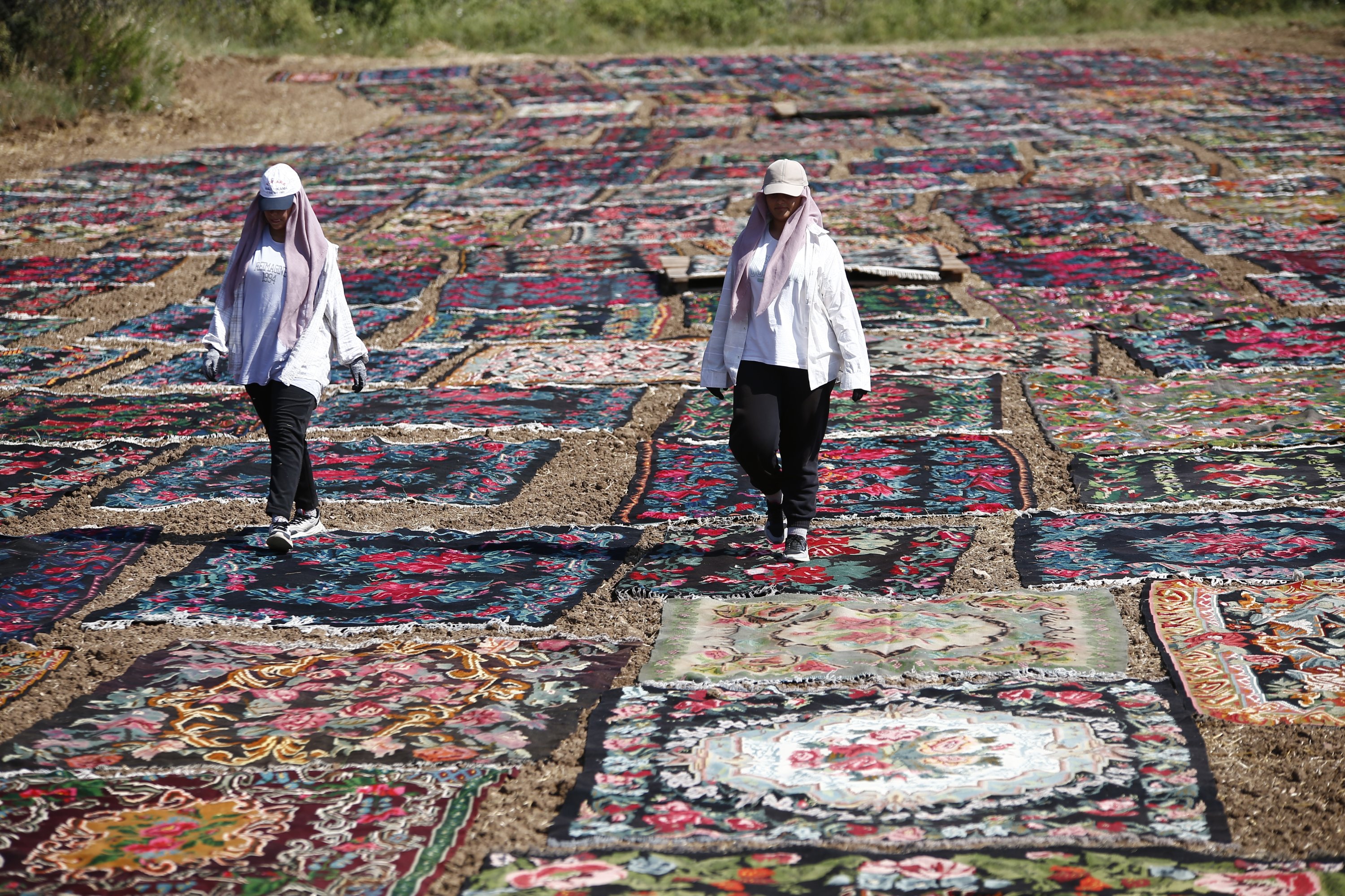 Wanita berjalan di atas karpet yang dijemur di ladang, Antalya, Türkiye selatan, 20 Juli 2023. (Foto AA)