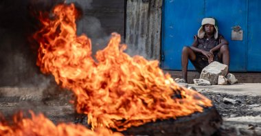 A young Kenyan sits next to a burning barricade used to block a main road during the third day of anti-government protests, Nairobi, Kenya, July 21, 2023. (AFP Photo)