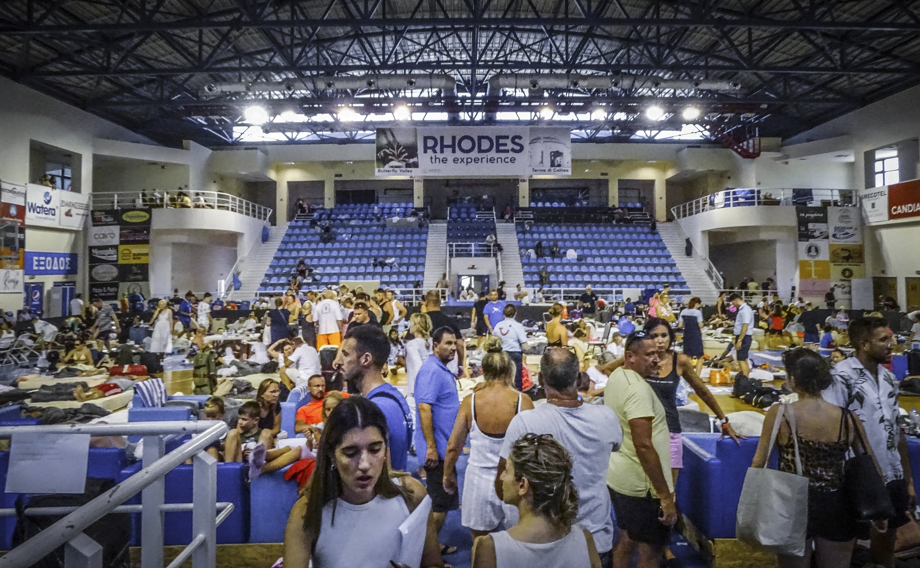 Pengungsi duduk di dalam stadion saat terjadi kebakaran hutan di pulau Rhodes, Yunani, 23 Juli 2023. (Foto AP)