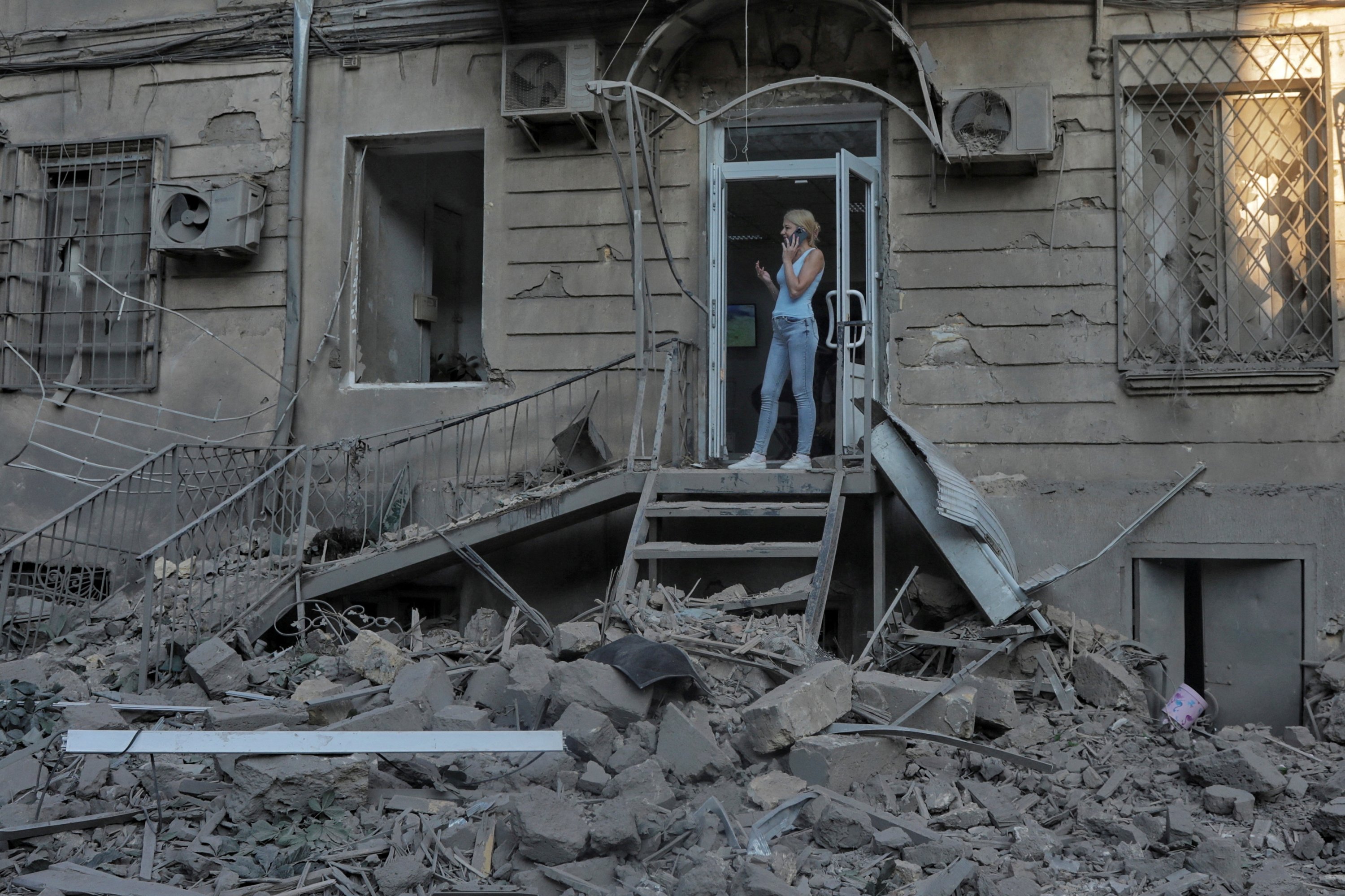 Seorang wanita berbicara melalui ponselnya di samping bangunan yang rusak akibat serangan rudal Rusia di Odessa, Ukraina, 23 Juli 2023. (Foto Reuters)