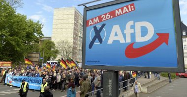 AfD supporters walk along a party elections poster in Erfurt, Germany, May 1, 2019. (AP Photo)