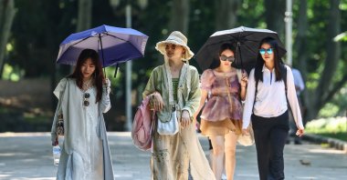 Tourists walk with umbrellas as they visit Gülhane Park on a hot summer day in Istanbul, Türkiye, 11 July 2023. (EPA Photo)