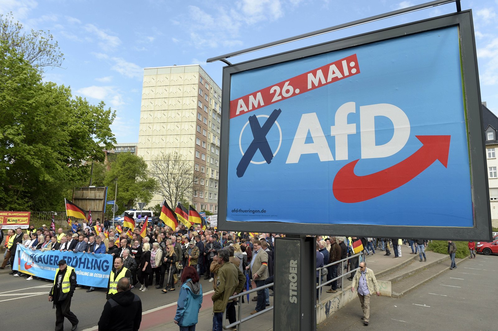 AfD supporters walk along a party elections poster in Erfurt, Germany, May 1, 2019. (AP Photo)