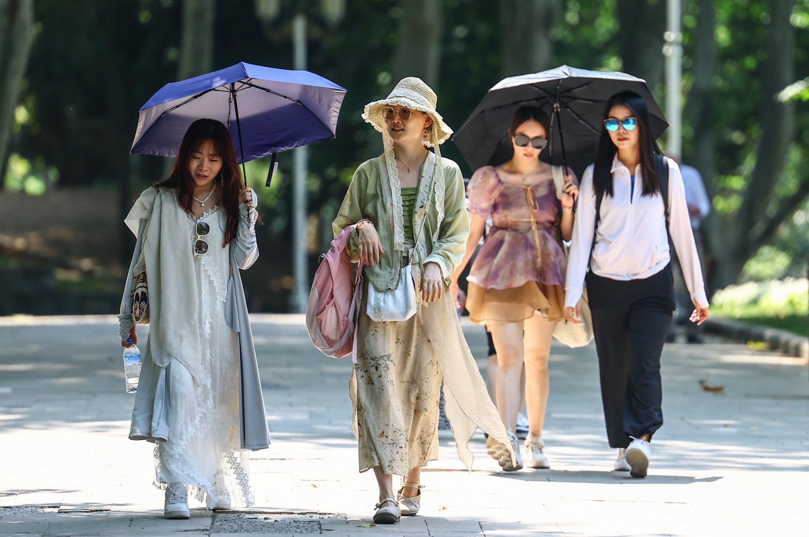 Tourists walk with umbrellas as they visit Gülhane Park on a hot summer day in Istanbul, Türkiye, 11 July 2023. (EPA Photo)