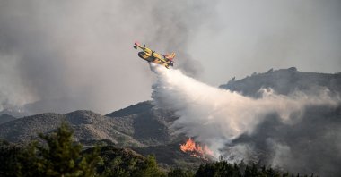 A firefighting aircraft drops water over a wildfire on the island of Rhodes, Greece, July 25, 2023. (AFP Photo)