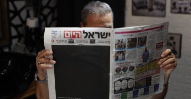 An Israeli hairdresser reads &#039;Israel Hayom&#039; (Israel Today) with a blacked out front page and headline reading in Hebrew &#039;Black Day for Israeli Democracy,&#039; Jerusalem, July 25, 2023. (EPA Photo)