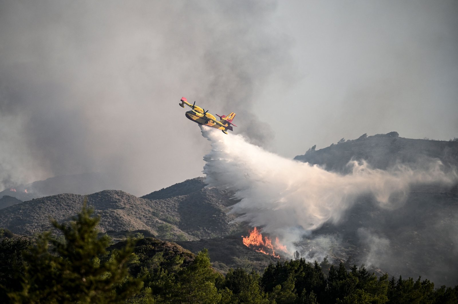 A firefighting aircraft drops water over a wildfire on the island of Rhodes, Greece, July 25, 2023. (AFP Photo)