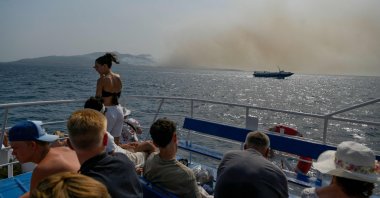 Tourists ride on a ferry to Corfu island as the smoke billows from the fire over the island, Greece, July 25, 2023. (AFP Photo)