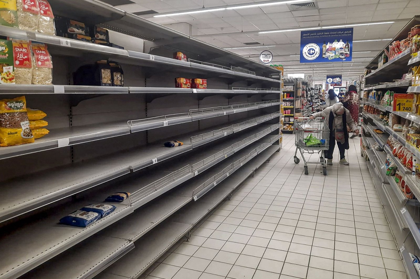 A shopper walks past empty shelves in a supermarket alley amidst a shortage of coffee, milk, pasta, and sugar in Tunis, Tunisia, Jan. 12, 2023. (AFP Photo)