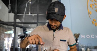 A specialty coffee shop employee weighs a cupful of roast coffee grains before grinding them at the shop in Sanaa, Yemen's Houthi-held capital, July 23, 2023. (AFP Photo)