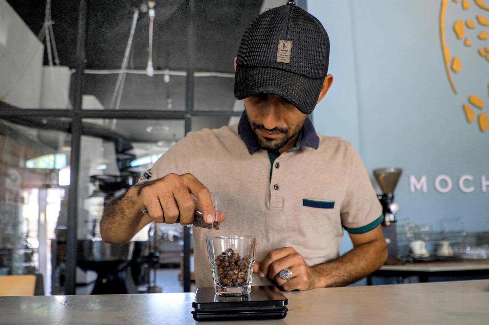 A specialty coffee shop employee weighs a cupful of roast coffee grains before grinding them at the shop in Sanaa, Yemen&#039;s Houthi-held capital, July 23, 2023. (AFP Photo)