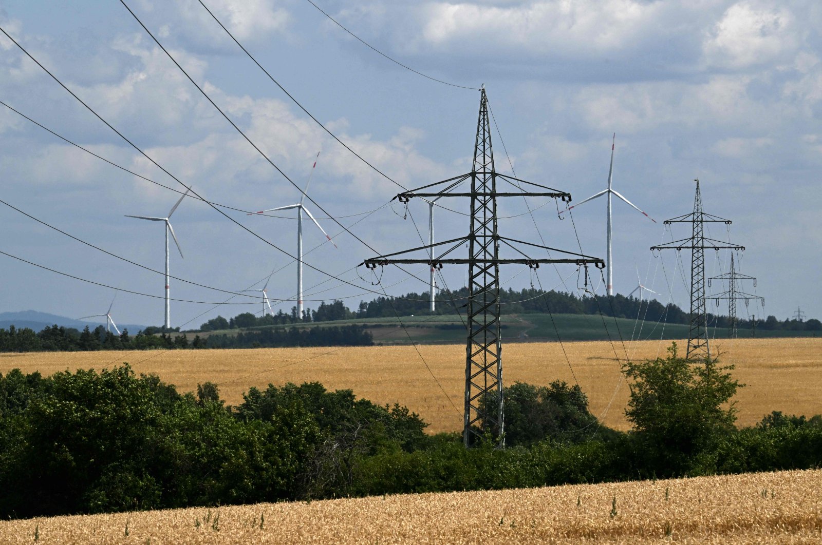 Wind turbines stand in the background of electricity pylons near the village of Bavarian in Schnabelwaid, southern Germany, July 17, 2023. (AFP Photo)