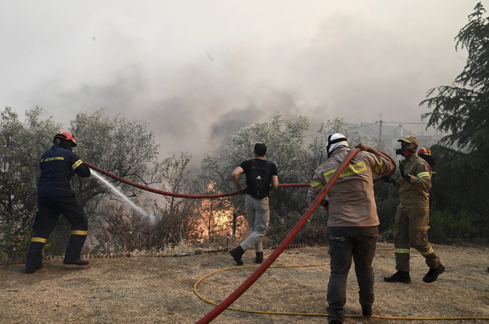 Firefighters and volunteers try to extinguish a wildfire in the town of Nea Anchialos, near Volos, central Greece, July 27, 2023. (AP Photo)