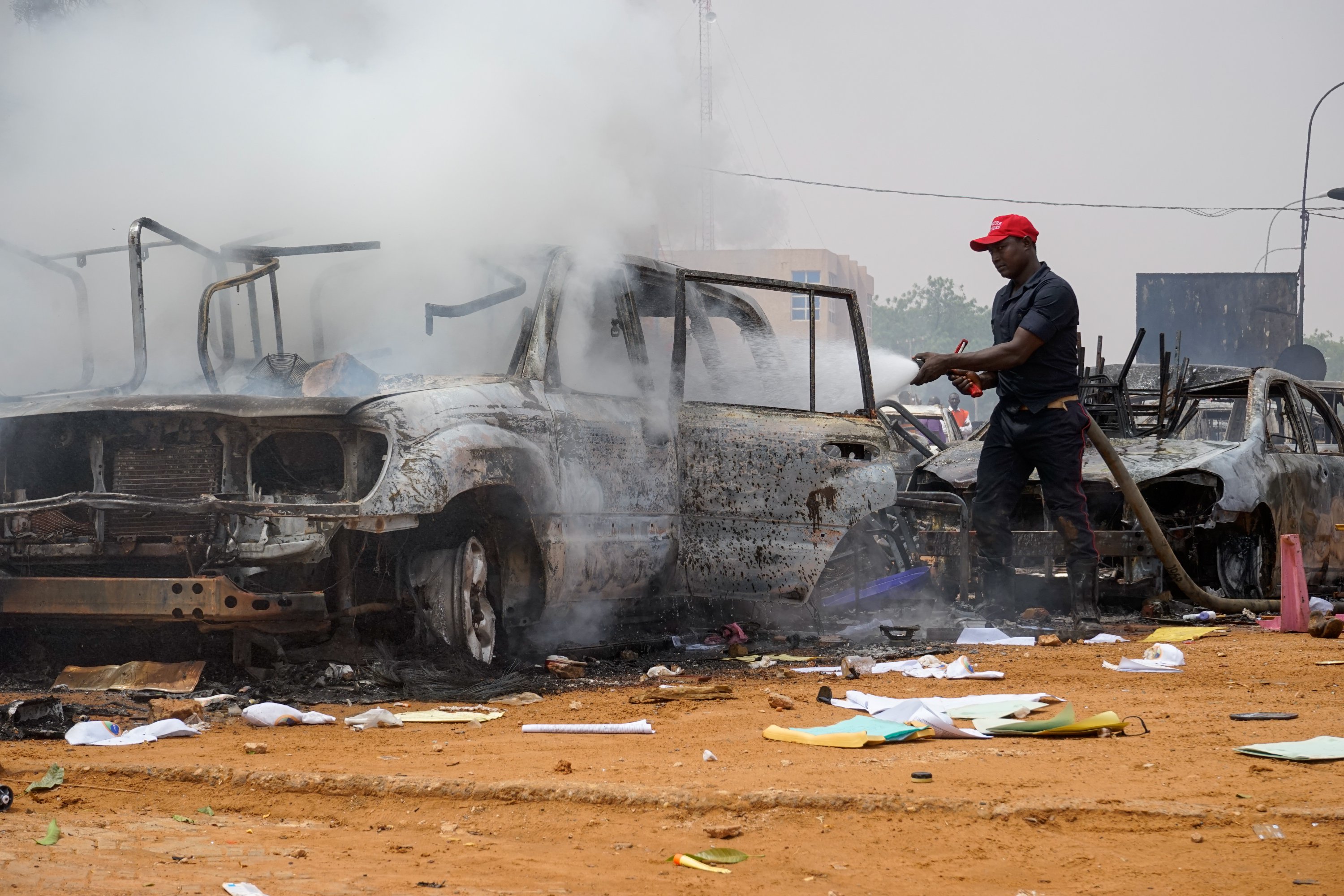 A firefighter hoses torched cars near the Nigerien Party for Democracy and Socialism headquarters in Niamey, Niger, July 27, 2023. (EPA Photo)