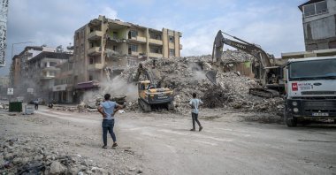 People watch as diggers work to clean the rubble of collapsed buildings, five months after devastating earthquakes hit southeastern Türkiye, in Samandağ, Hatay, July 9, 2023. (AFP Photo)