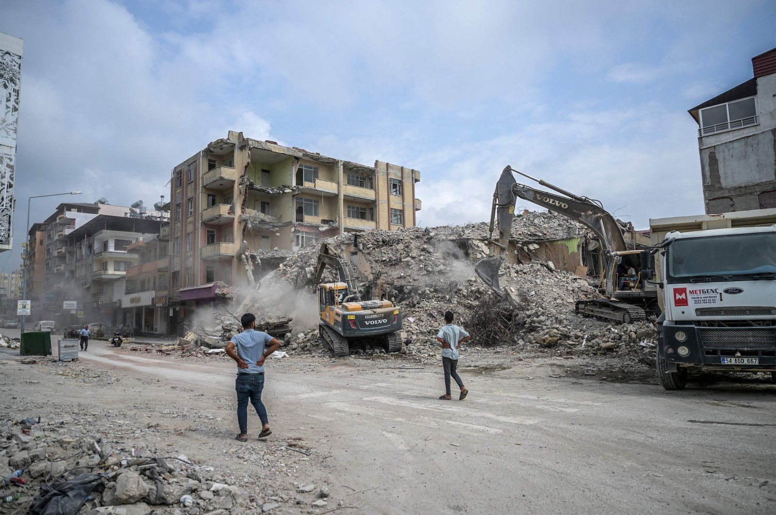 People watch as diggers work to clean the rubble of collapsed buildings, five months after devastating earthquakes hit southeastern Türkiye, in Samandağ, Hatay, July 9, 2023. (AFP Photo)