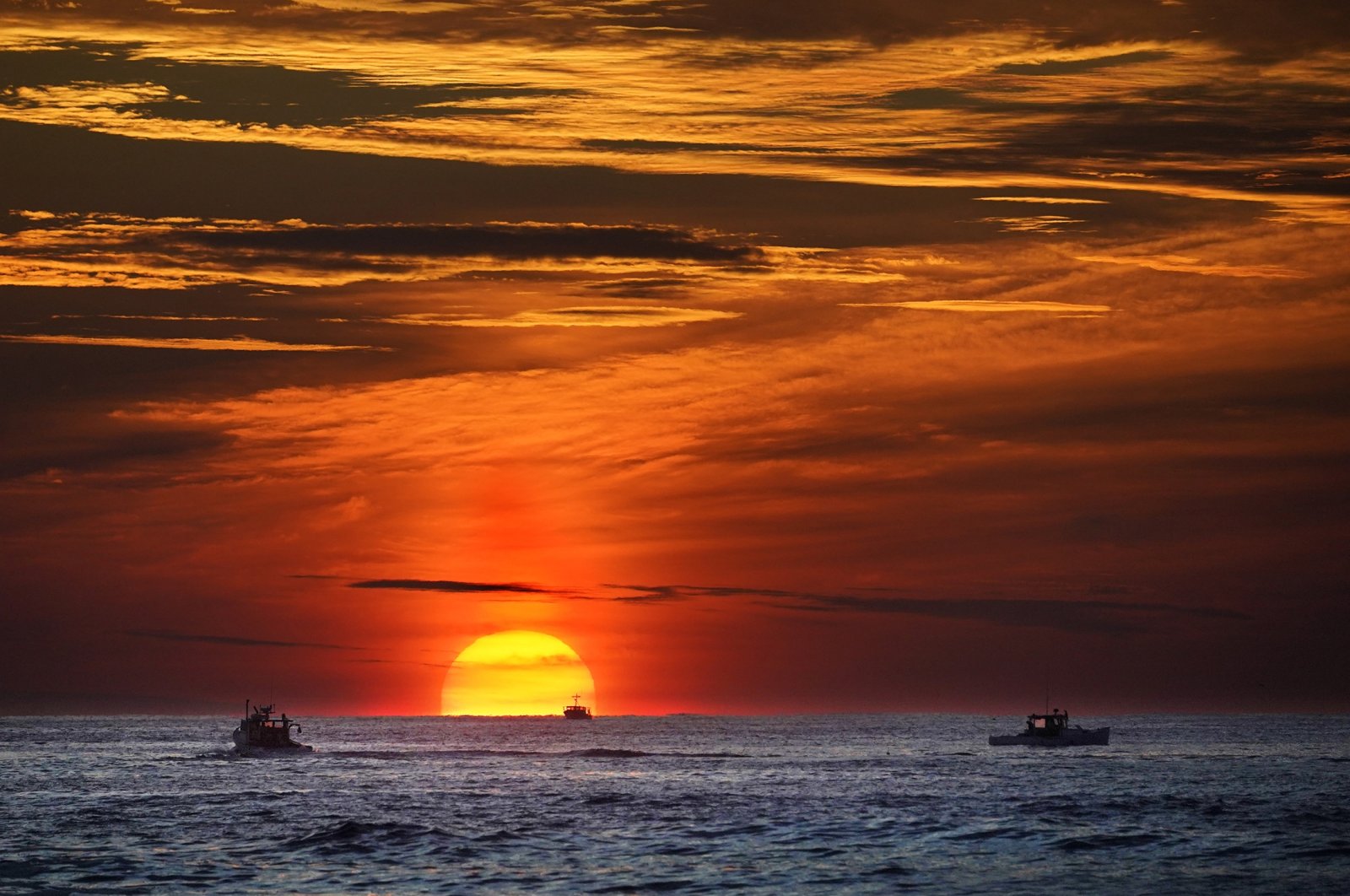 The sun rises over fishing boats in the Atlantic Ocean off of Kennebunkport, Maine, U.S., Sept. 8, 2022. (AP Photo)