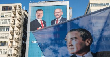 A flag portraying Mustafa Kemal Atatürk (R), founder of the Turkish Republic, seen in front of a poster with Republican People's Party (CHP) chair Kemal Kılıçdaroğlu (C) and Istanbul's mayor Ekrem Imamoğlu (L) in Mecidiyeköy's square, Istanbul, Türkiye, May 22, 2023. (Getty Images Photo)
