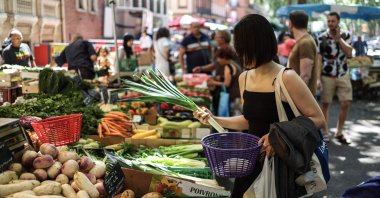 A woman buys vegetables at an outdoor market in Toulouse, southwestern France, July 8, 2023. (AFP Photo)