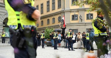 Policemen stand next to demonstrators, among them a protester (background, C) holding the flag of Iraq, at Mynttorget Square in Stockholm, Sweden, July 31, 2023. (AFP Photo)