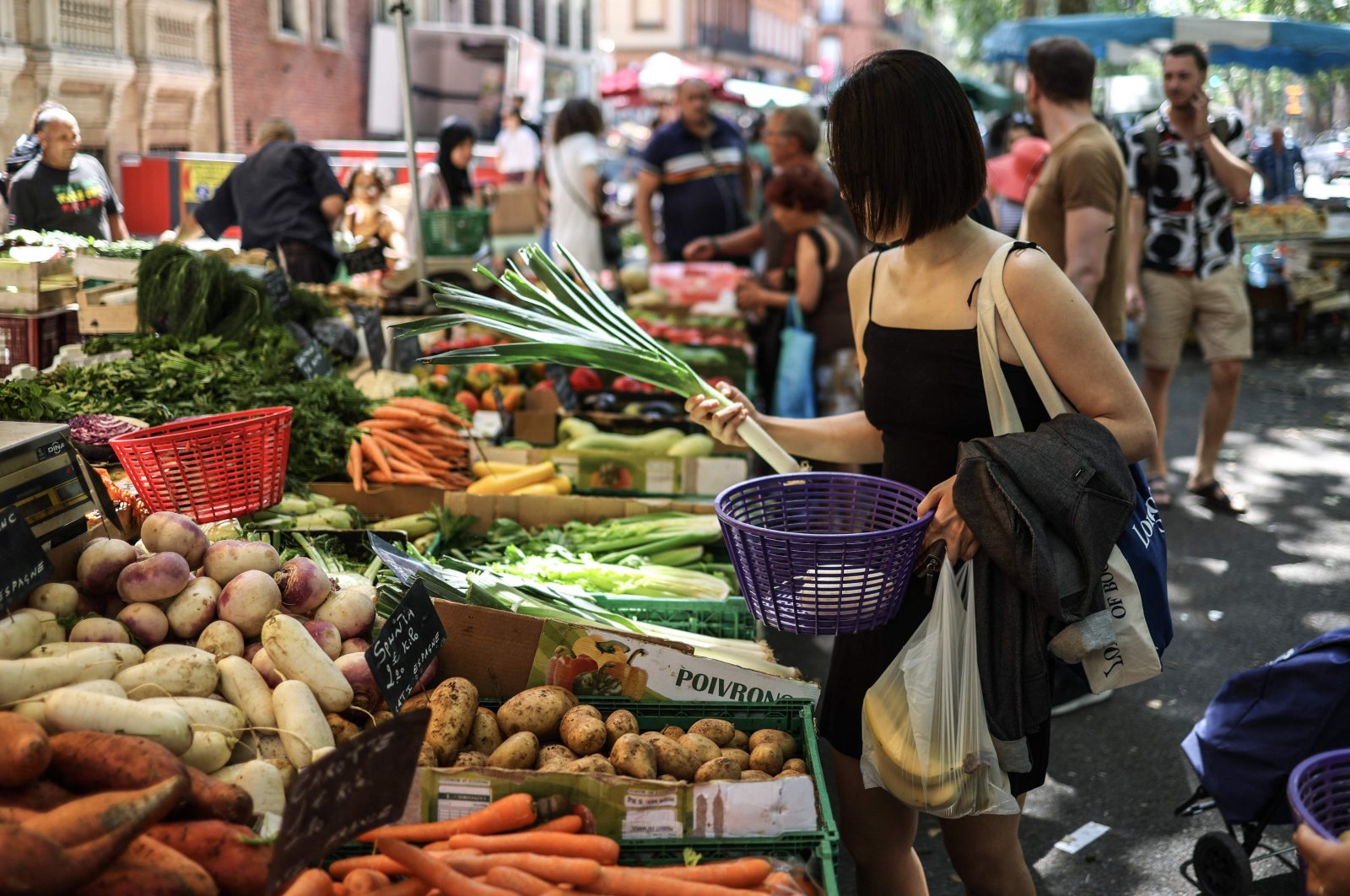 A woman buys vegetables at an outdoor market in Toulouse, southwestern France, July 8, 2023. (AFP Photo)