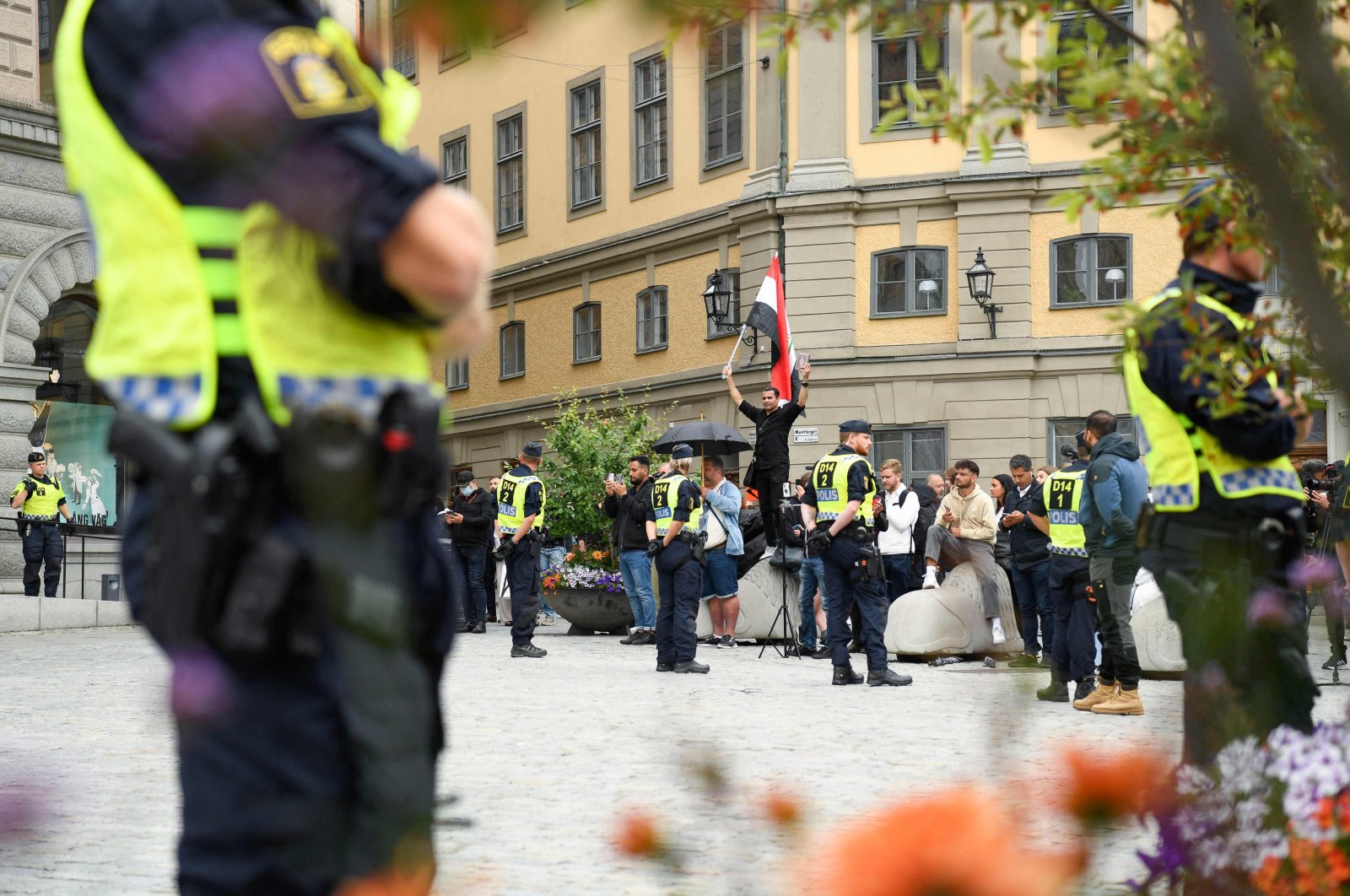 Policemen stand next to demonstrators, among them a protester (background, C) holding the flag of Iraq, at Mynttorget Square in Stockholm, Sweden, July 31, 2023. (AFP Photo)
