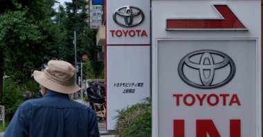A man walks past signboards for a Toyota Motor car showroom in Tokyo on August 4, 2022. (Photo by Kazuhiro NOGI / AFP)