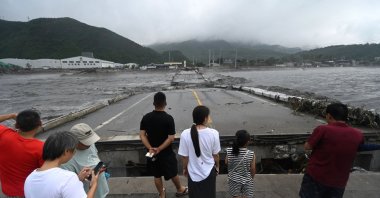 People watch a collapsed bridge on the Dashihe River after heavy rains in Fangshan district in Beijing, China, Aug. 1, 2023. (AFP Photo)