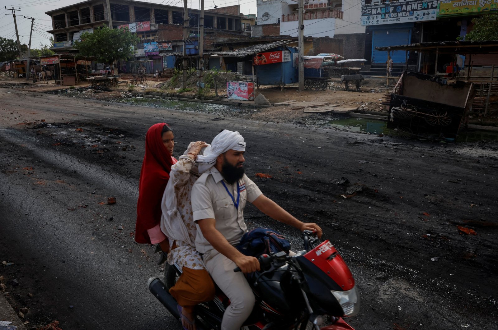 A family rides on a motorcycle on a deserted road during a curfew following Hindu-Muslim clashes in Nuh, Haryana, northern India, Aug. 1, 2023. (Reuters Photo)