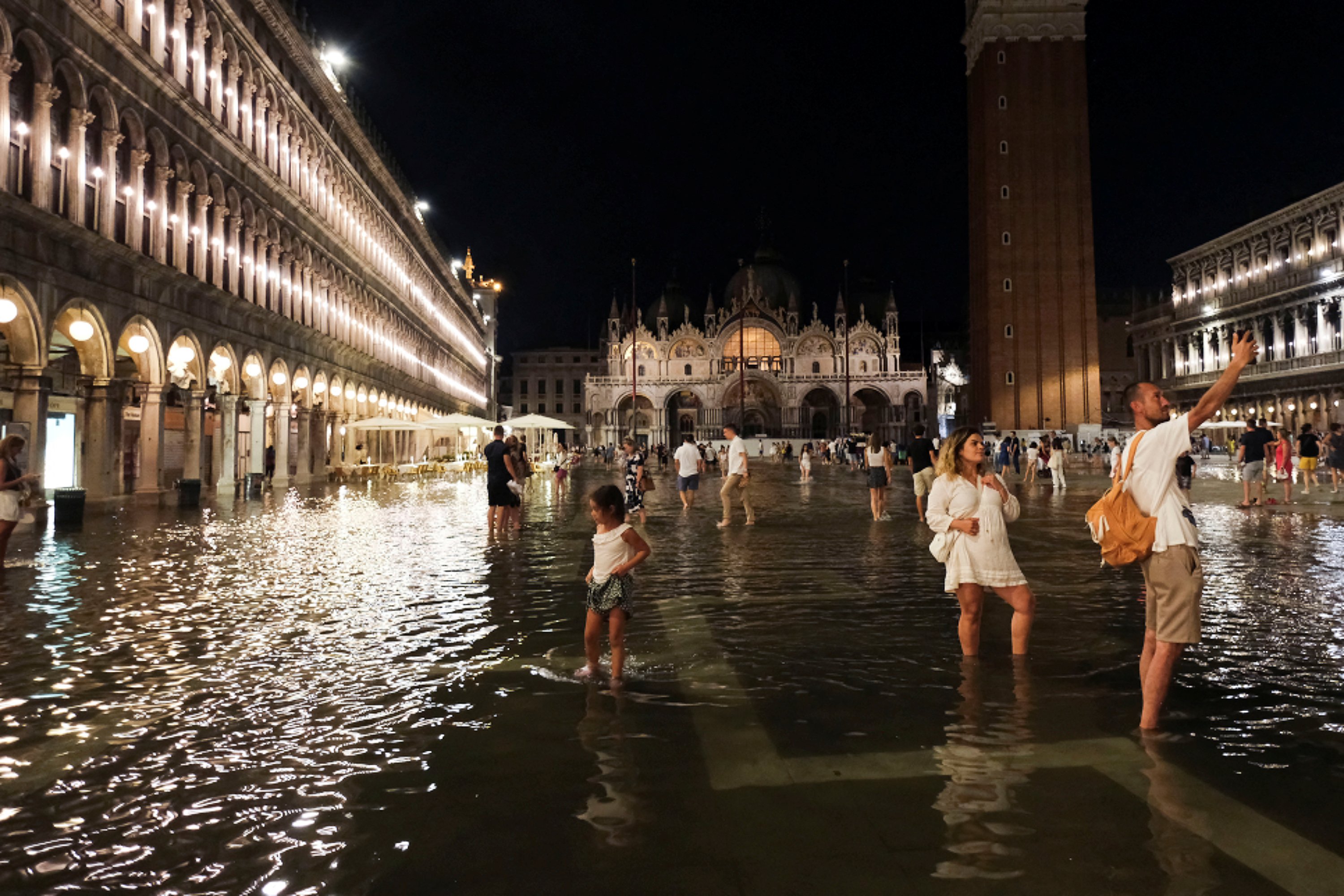 Tourists walk through flooded St Mark's Square after unusually high water levels in Venice, Italy, August 1, 2023. (Reuters Photo)