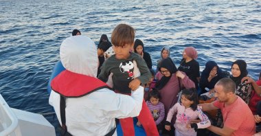Turkish coast guard pulls a child up on a rescue vessel as they rescue 42 irregular migrants pushed back by Greece off the coast Ayvacık, western Çanakkale province, Türkiye, July 31, 2023. (AA Photo)