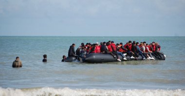 Migrants sit onboard an inflatable boat before attempting to illegally cross the English Channel to reach Britain, off the coast of Sangatte, France, July 18, 2023. (AFP Photo) 