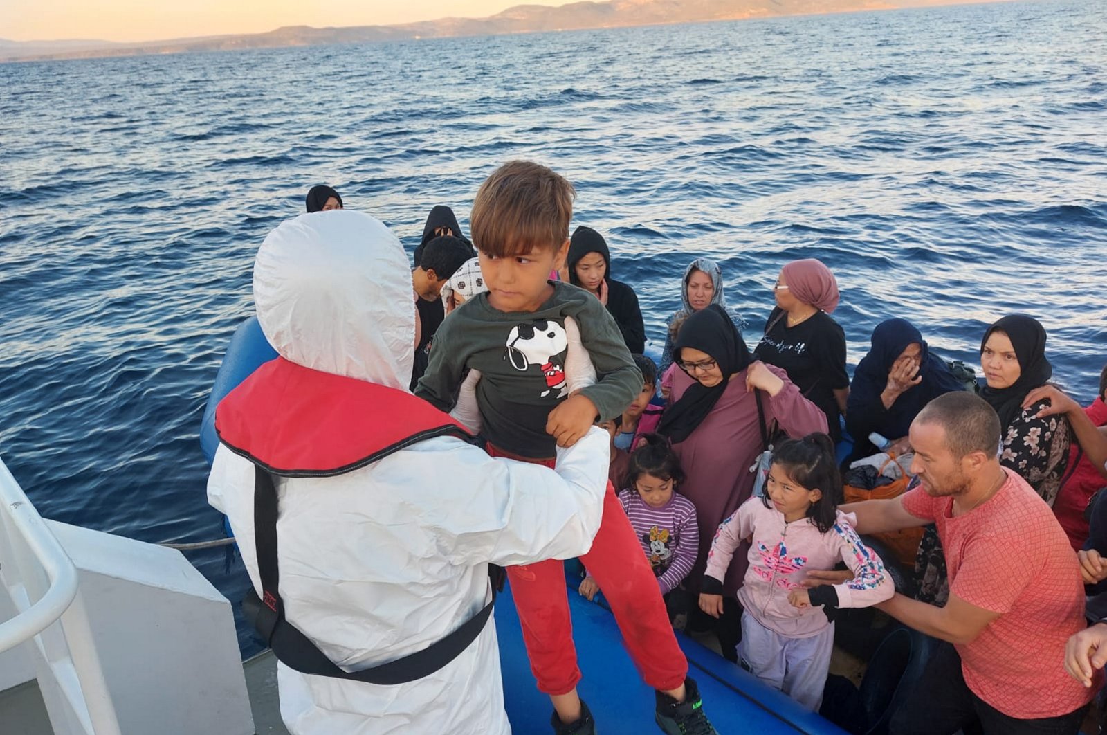 Turkish coast guard pulls a child up on a rescue vessel as they rescue 42 irregular migrants pushed back by Greece off the coast Ayvacık, western Çanakkale province, Türkiye, July 31, 2023. (AA Photo)