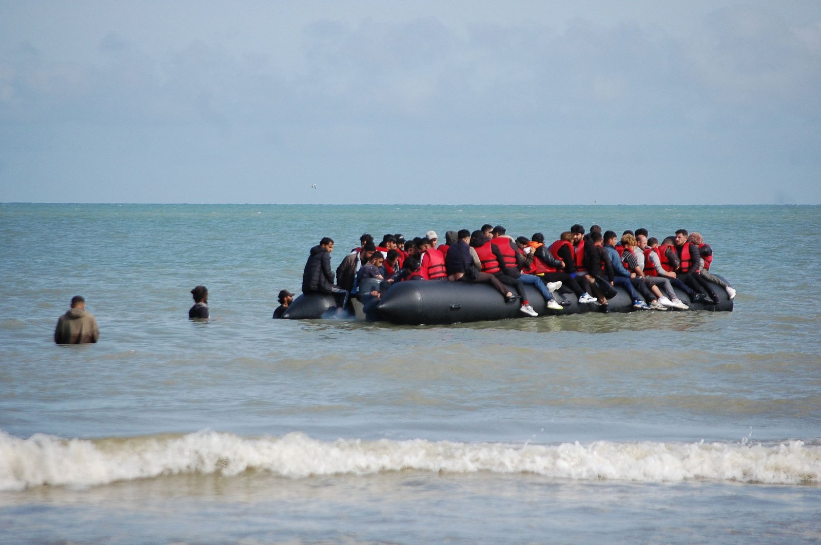 Migrants sit onboard an inflatable boat before attempting to illegally cross the English Channel to reach Britain, off the coast of Sangatte, France, July 18, 2023. (AFP Photo) 
