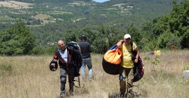 Paraglider Nedim Küçük (R) walks after landing at Mt. Hasan, Aksaray, Türkiye, July 30, 2023. (AA Photo)