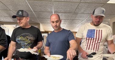 Maksym Bunchukov (L), Andrii Hryshchuk (C) and Ivan Sakivskyi help themselves to perogies at a lunch hosted on July 17, 2023, by the Ukrainian Cultural Institute in Dickinson, North Dakota. (AP Photo)