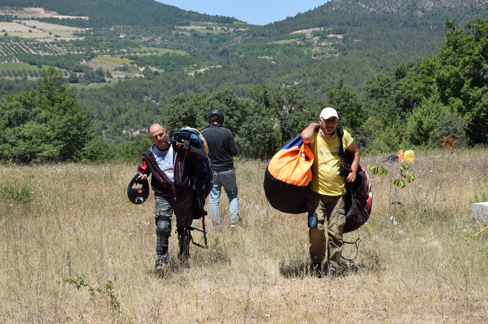 Paraglider Nedim Küçük (R) walks after landing at Mt. Hasan, Aksaray, Türkiye, July 30, 2023. (AA Photo)