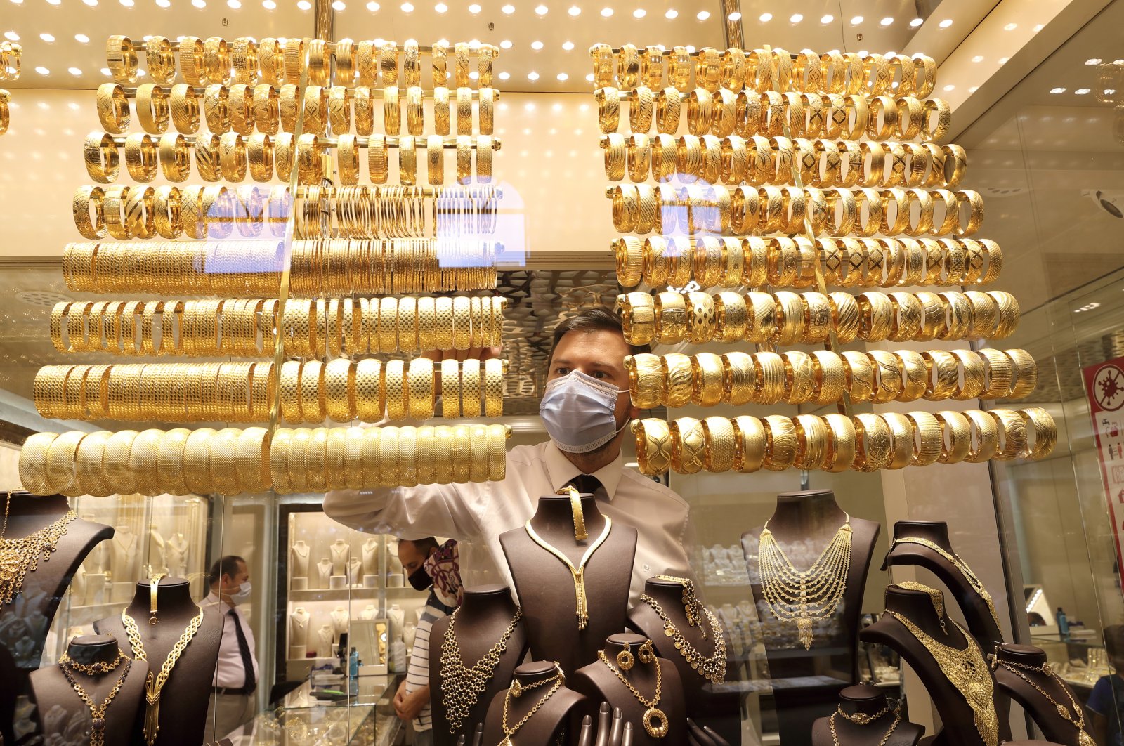 A shop owner arranges golden bangles at a jewelry shop at the Grand Bazaar in Istanbul, Türkiye, Aug. 6, 2020. (Reuters Photo)