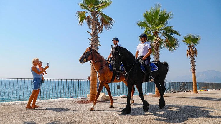 Tourists taking photos of mounted police officers patrolling the area close to Konyaaltı Beach, Antalya, southern Türkiye, Aug. 8, 2023. (DHA Photo)