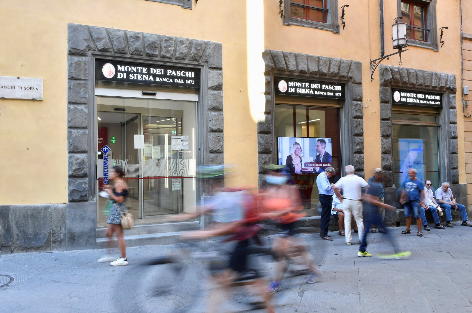 People pass in front of a branch of Monte dei Paschi di Siena (MPS), the oldest bank in the world, in Siena, Italy, Aug. 11 2021. (Reuters Photo)