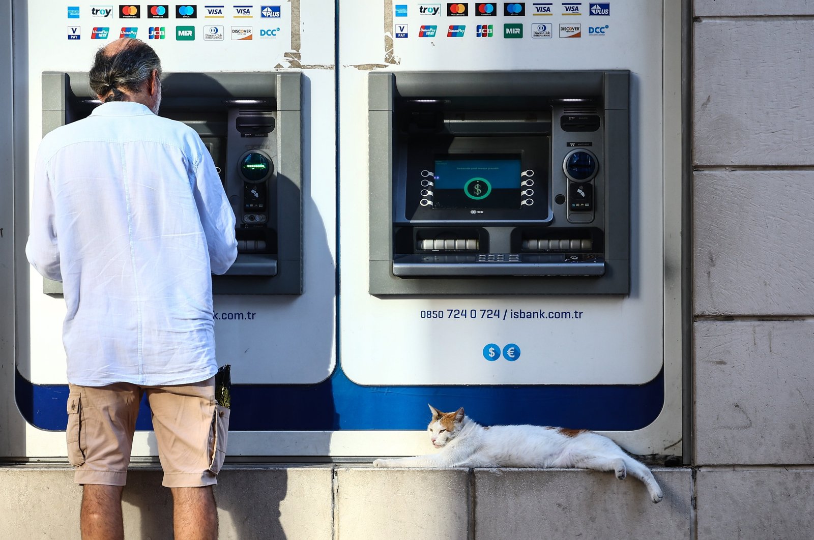 A stray cat sleeps in front of an ATM in Istanbul, Türkiye, Aug. 8, 2023. (EPA Photo)