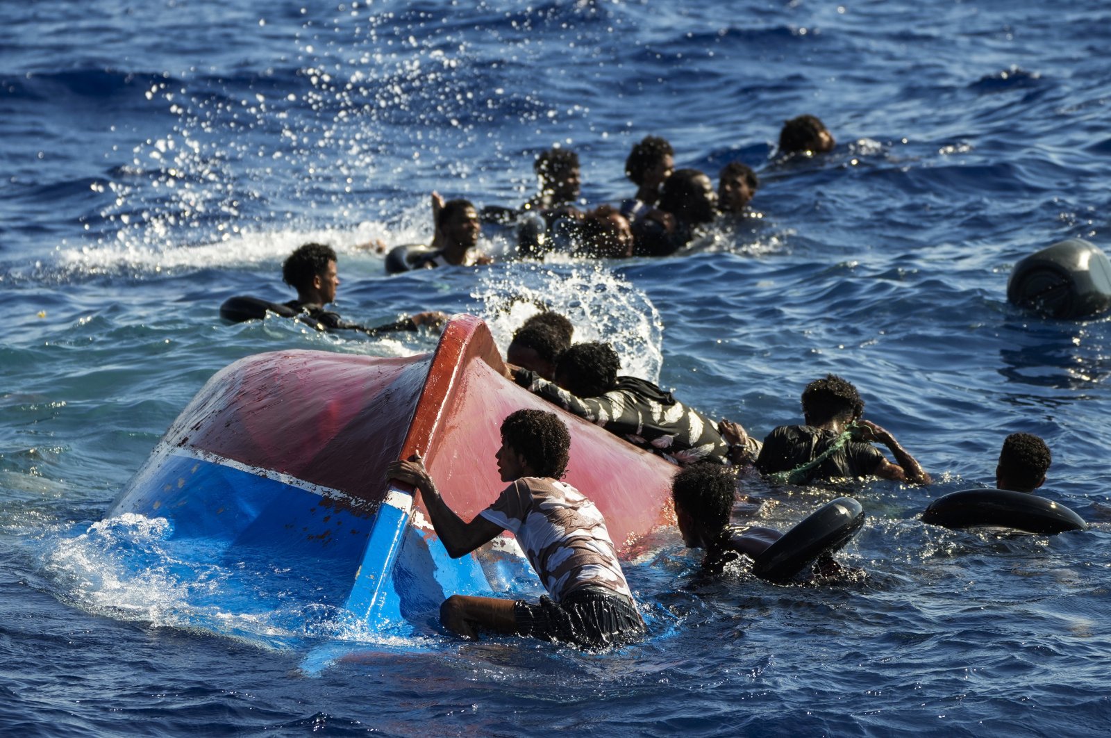 Migrants swim next to their overturned wooden boat during a rescue operation by Spanish NGO Open Arms south of the Italian Lampedusa island in the Mediterranean Sea, Thursday, Aug. 11, 2022. (AP File Photo)