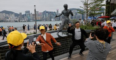 Chinese tourists pose for photos in front of a statue of the martial artist and actor Bruce Lee, on the Avenue of Stars attraction near the Tsim Sha Tsui waterfront, in Hong Kong, China, April 26, 2023. (Reuters Photo)