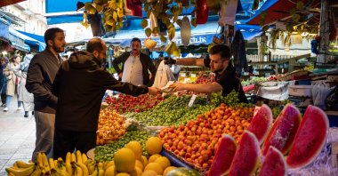 A customer hands a vendor Turkish lira banknotes to pay for goods at a fruit and vegetable stall at a local market in Bursa, Türkiye, May 18, 2023. (Getty Images Photo)