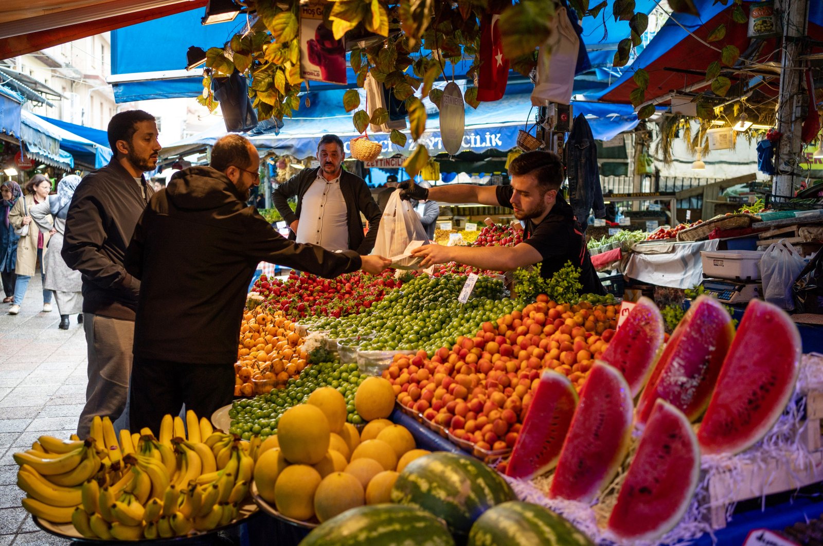 A customer hands a vendor Turkish lira banknotes to pay for goods at a fruit and vegetable stall at a local market in Bursa, Türkiye, May 18, 2023. (Getty Images Photo)