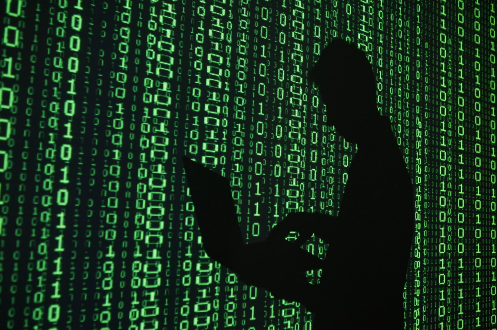 An illustration picture shows a projection of binary code around the shadow of a man holding a laptop computer. (Reuters Photo)