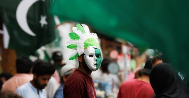 A vendor wears a mask and a headwear with the colours of the Pakistani flag, while selling national flags and patriotic memorabilia, ahead of Pakistan&#039;s Independence Day, along a market in Karachi, Pakistan, Aug. 2, 2023. (Reuters Photo)